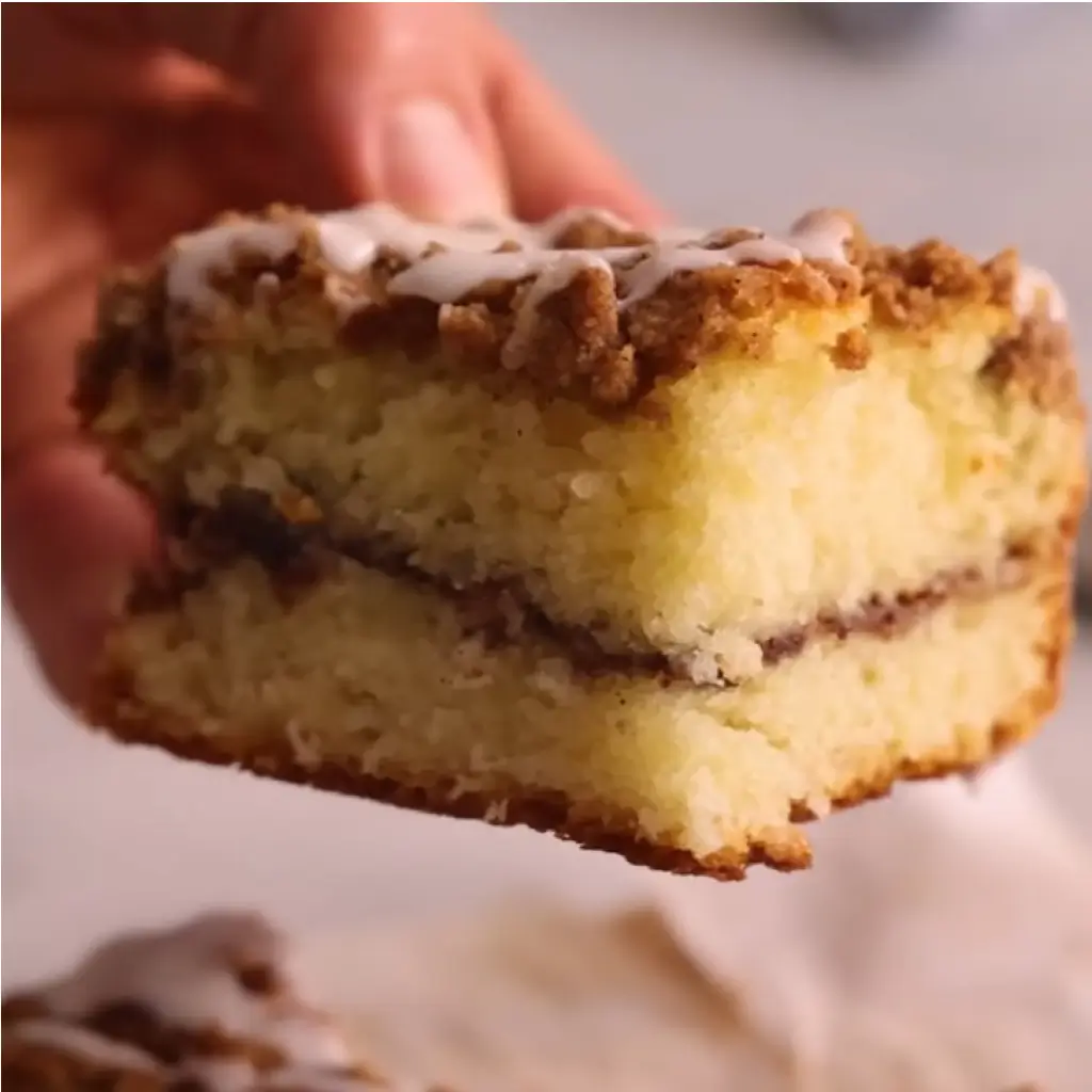 Moist homemade coffee cake with cinnamon sugar layer and crumb topping — easy coffee cake recipe slice held in hand