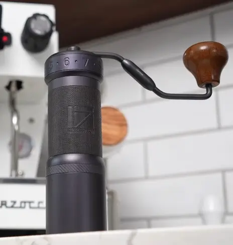 1Zpresso K-Ultra manual coffee grinder with wooden handle on white kitchen counter next to espresso machine
