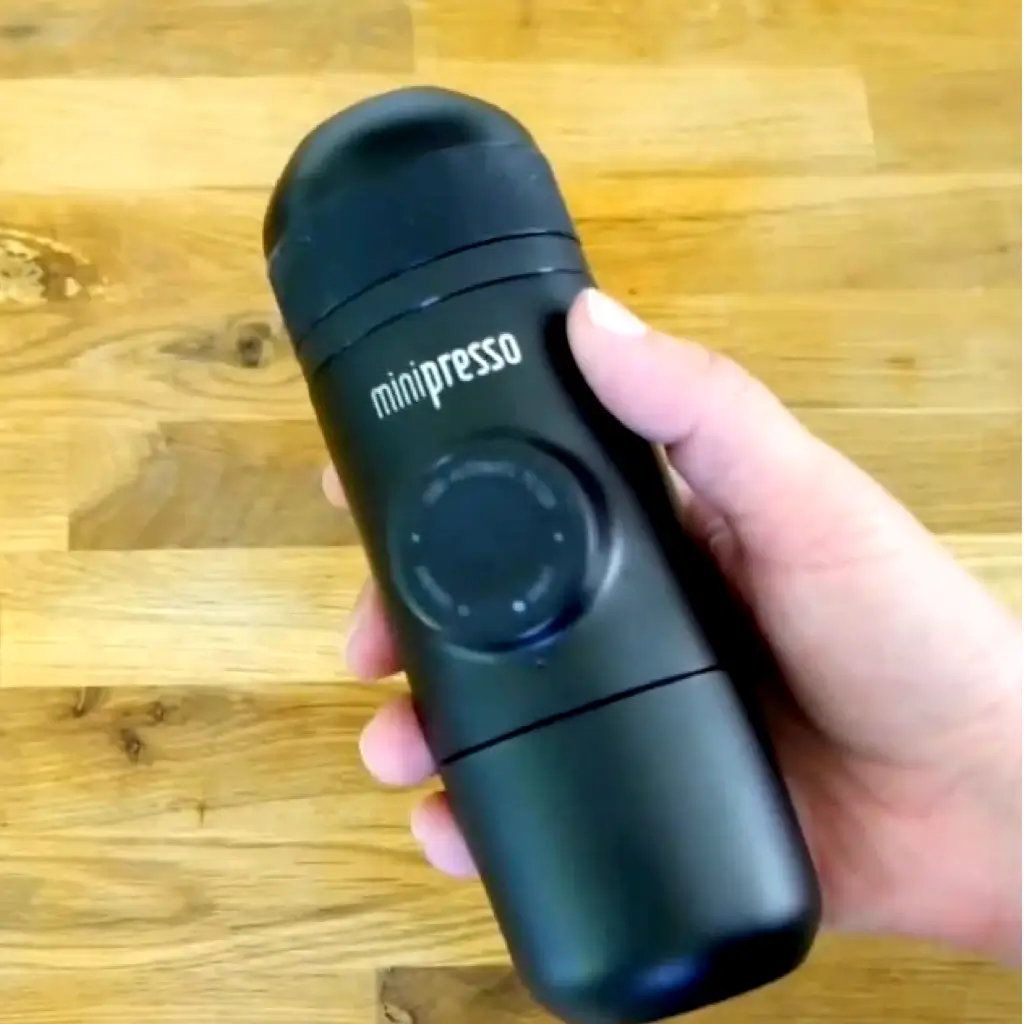 Wacaco Minpresso GR manual espresso machine held in hand, portable handheld coffee maker for travel and home