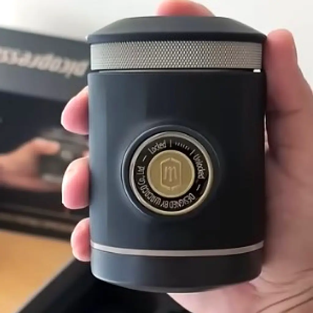 Wacaco Picopresso portable manual espresso machine held in hand showing compact black cylinder design with pressure valve